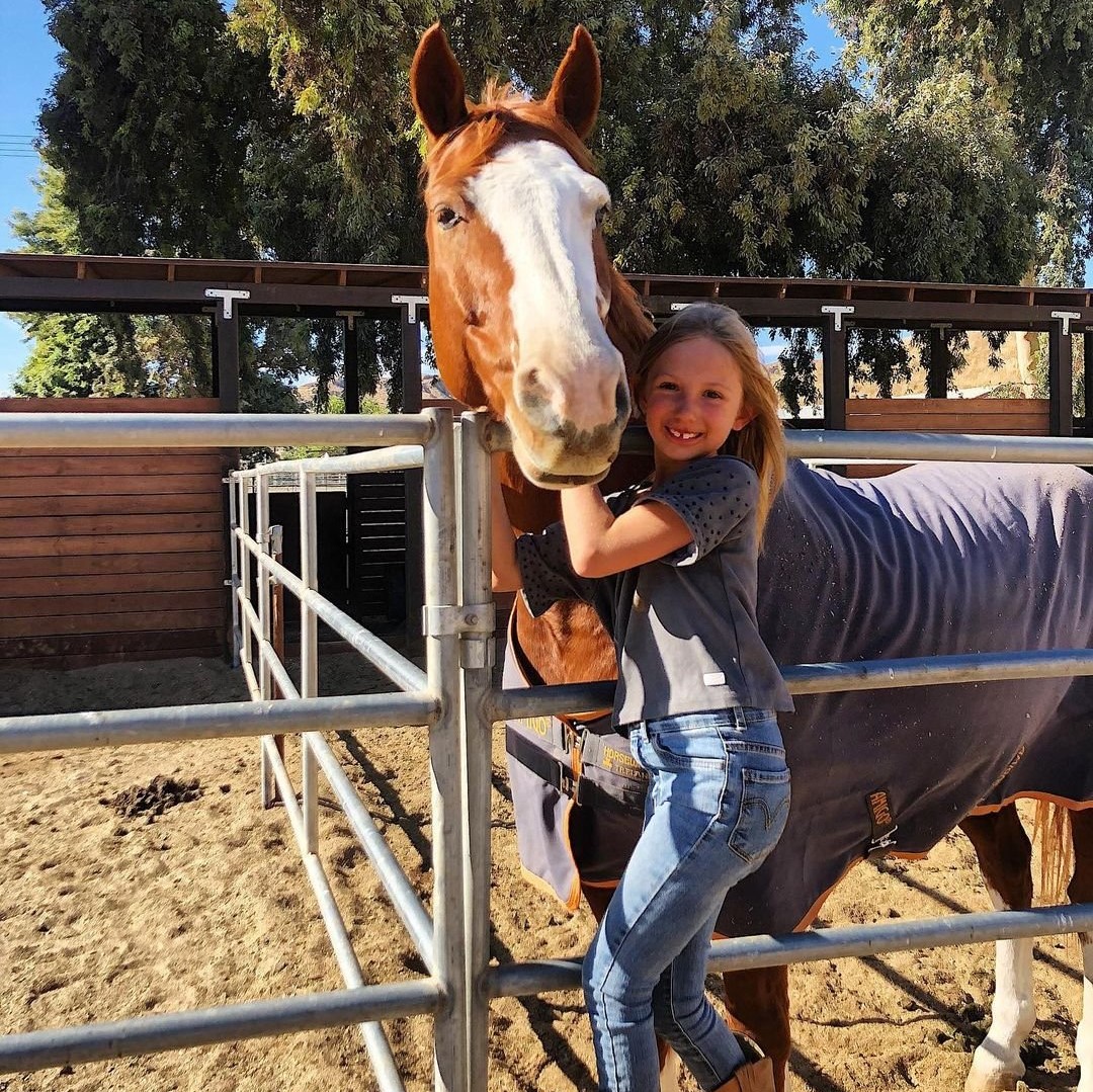 Little girl posing with a horse outside at the Santa Clarita Valley Equestrian Center.