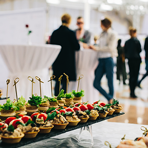 Table full of food with people socializing in the background at a nice event.