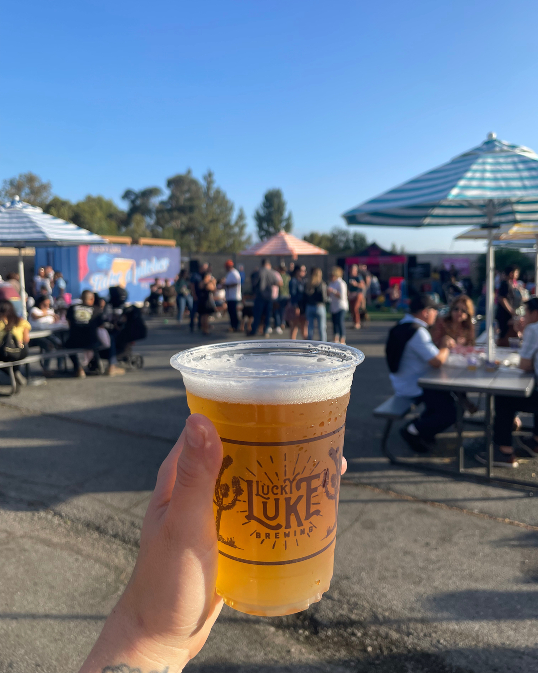 Person holding a beer outside at Lucky Luke Brewing Company in Santa Clarita.